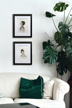 pair of smiling women portrait drawings hanging next to plant