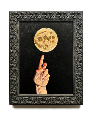 Framed hand reaching towards a golden full-moon against a dark background