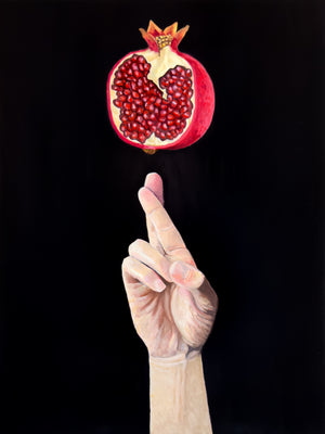 Hand with a cracked pomegranate against a black background