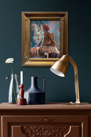 fairy painting with green wings and gold frame hanging on wall over side table