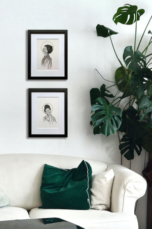 pair of smiling women portrait drawings hanging next to plant