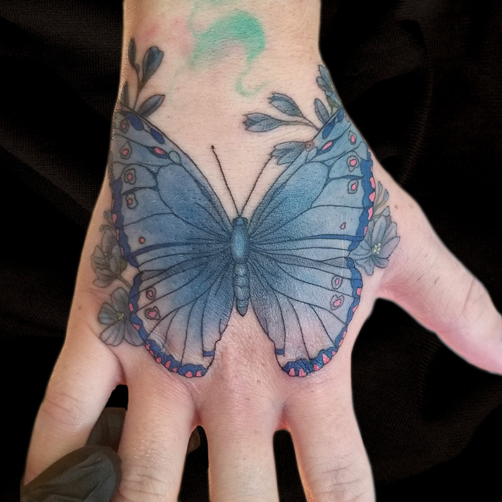 blue butterfly hand tattoo by Lydia Pitts