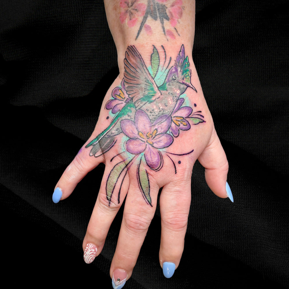 colorful hummingbird tattoo on hand by Cass Brown