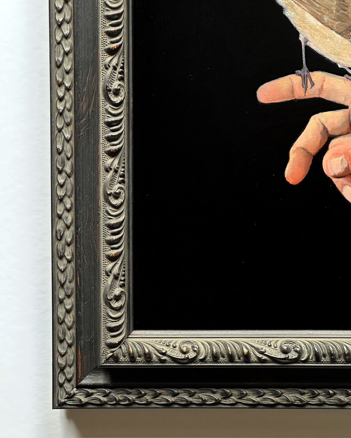 Close-up framed artistic depiction of a bird perched on a hand against a black background by Danny Schreiber