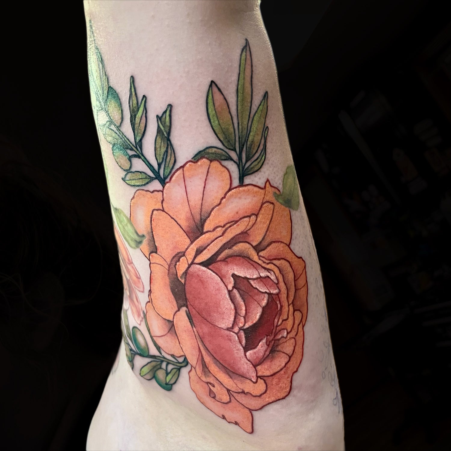 orange peony tattoo on inner bicep by Cass Brown