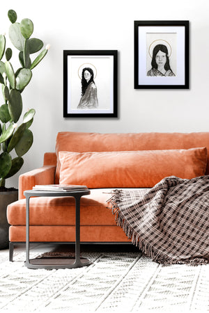 two portrait drawings of young women hanging over sofa