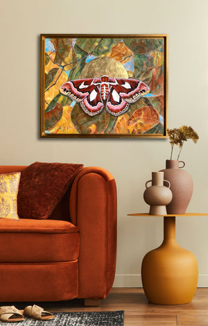 atlas moth leaf painting in gold frame on wall over chair