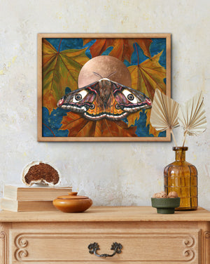 emperor moth art print with maple leaves in wood frame over dresser